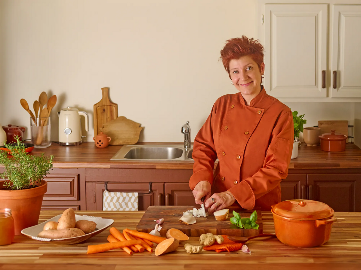 Annie Beauregard, chef et créatrice des recettes Pocket Soupe, coupe des oignons dans sa cuisine entourée de carottes, patates douces et gingembre