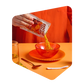 Poudre de soupe Pocket Soupe versée d'un sachet dans un bol de verre orange, sur une table dressée avec cuillère et verre d'eau
