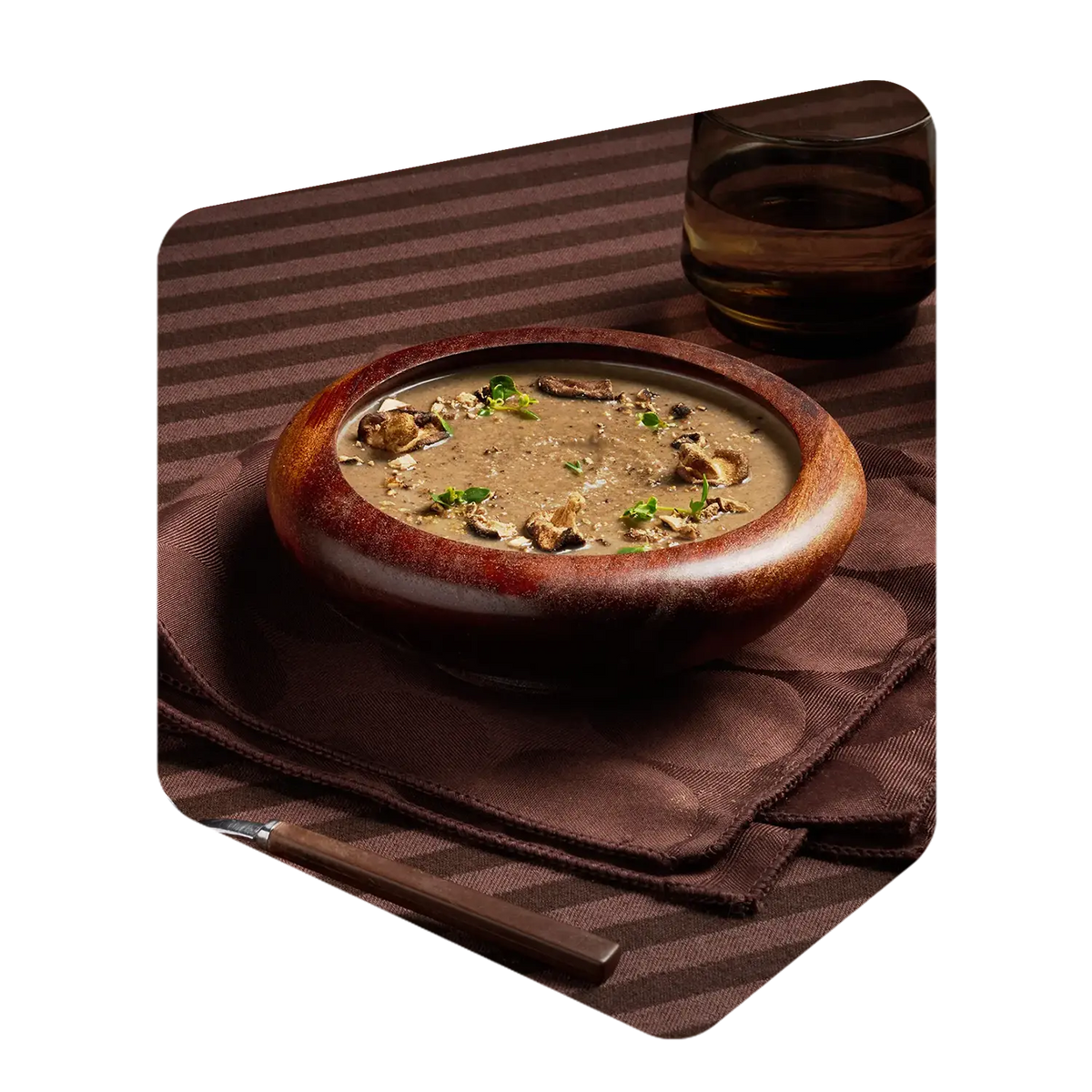 Bol de potage aux champignons Pocket Soupe garni de champignons séchés et de thym, servi sur une nappe brune