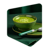 Bol de potage vert aux courgettes Pocket Soupe garni de graines, servi avec une cuillère sur une nappe verte
