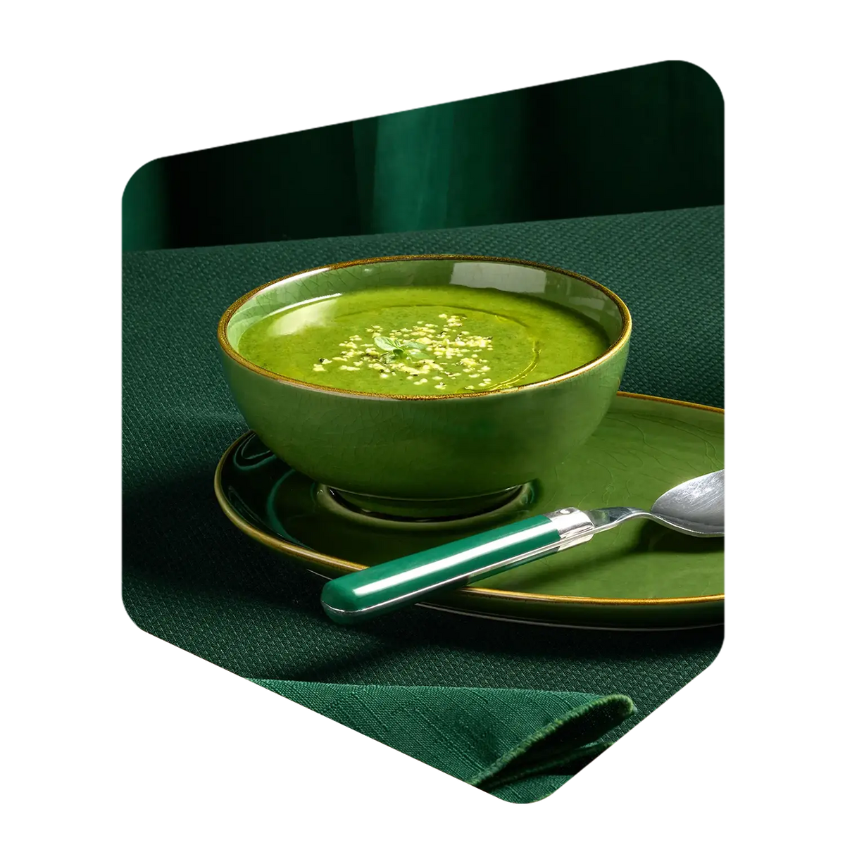 Bol de potage vert aux courgettes Pocket Soupe garni de graines, servi avec une cuillère sur une nappe verte