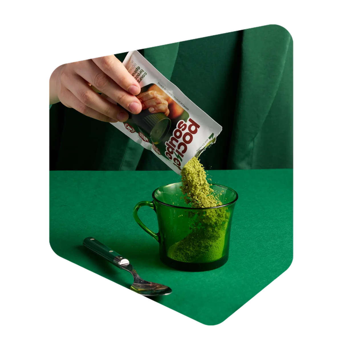 Poudre de potage aux courgettes Pocket Soupe versée d'un sachet dans une tasse de verre vert
