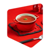 Cocotte rouge remplie de soupe aux tomates Pocket Soupe garnie de persil, posée sur un carré de laine tricoté